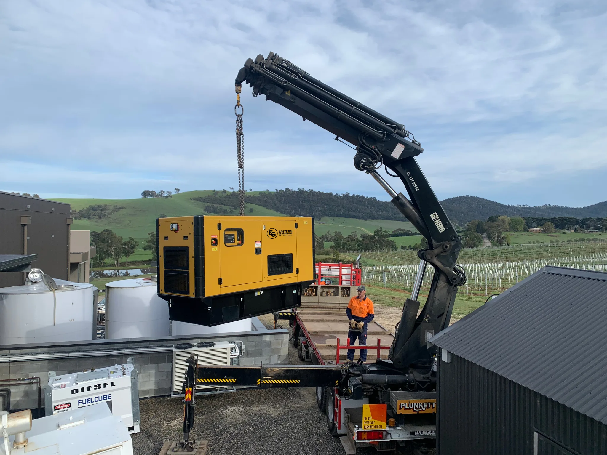 A truck-mounted crane placing a generator on site