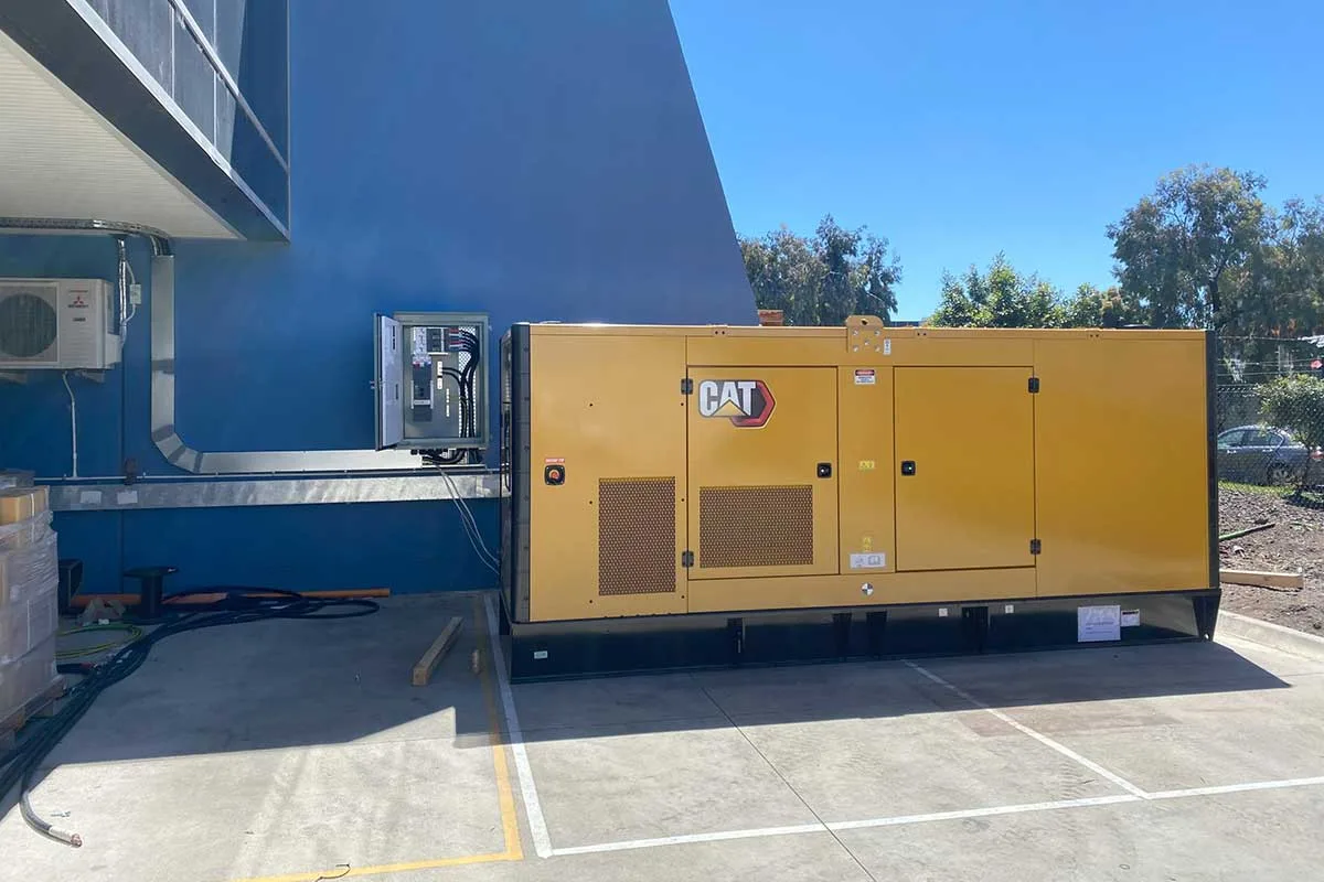 A large Caterpillar standby generator installed alongside a healthcare building