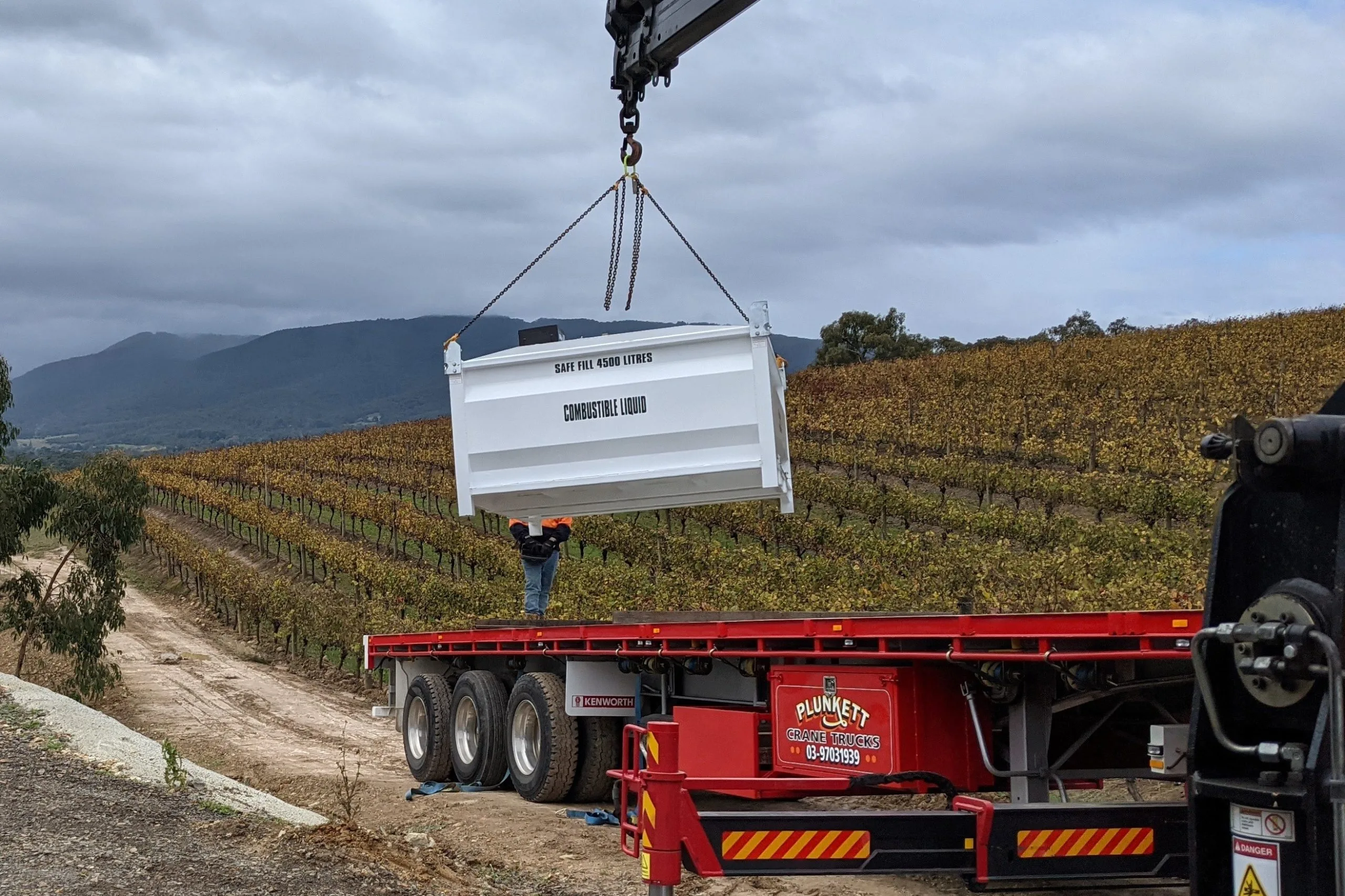 A bulk fuel tank being craned onto a trailer for an Eastern Generators site installation