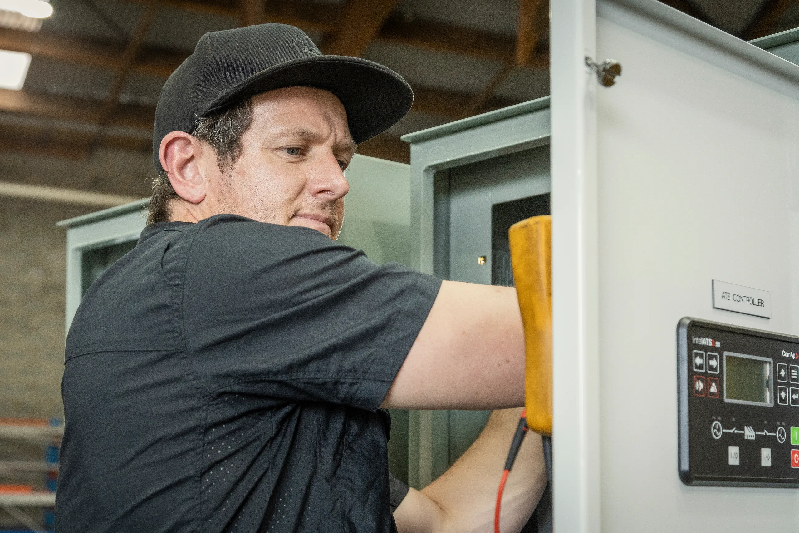 An Eastern Generators electrician working on a change-over controller in a switchboard