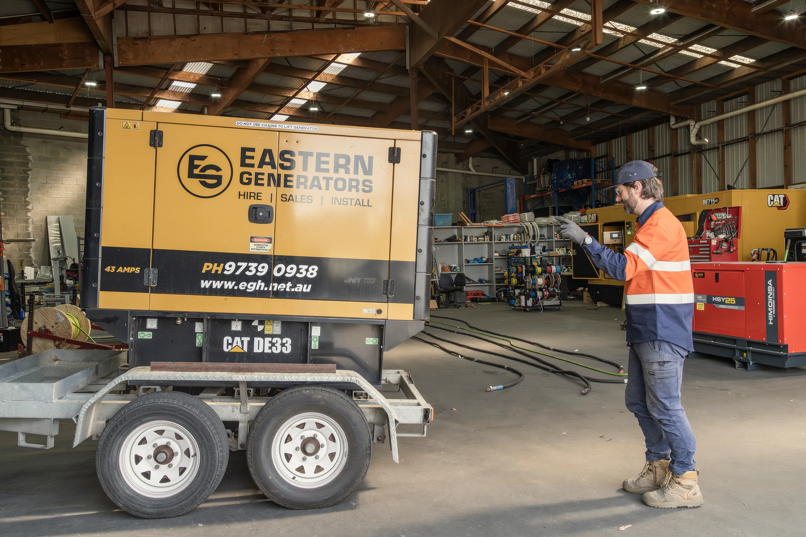 An Eastern Generators technician checking a trailer-mounted hire set in the workshop