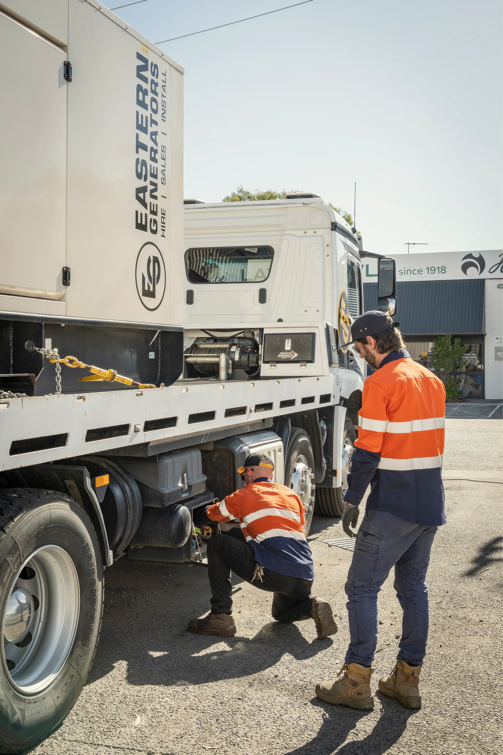 Crew checking the trailer under a large generator before a move